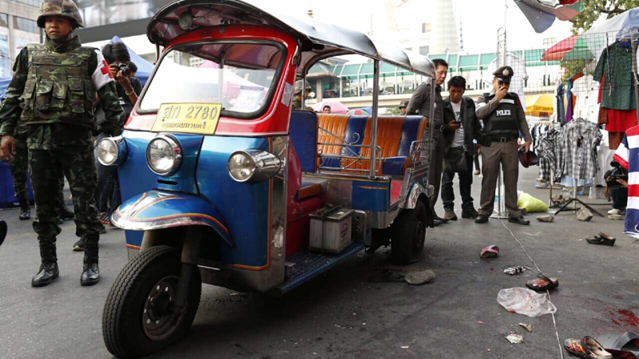 Thai soldiers secure the area while police inspect a bomb blast scene