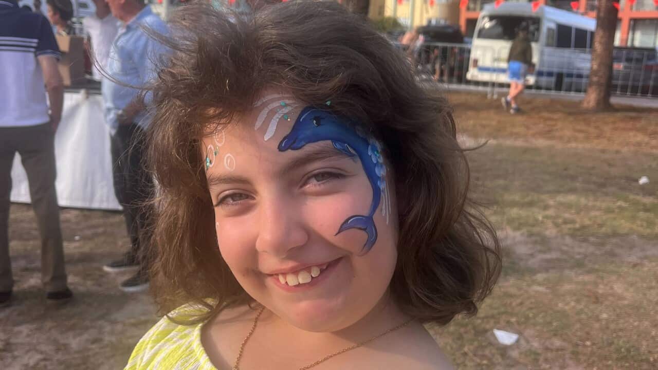 Ten-year-old Matilda in a yellow dress, smiling with a dolphin painted on her face.
