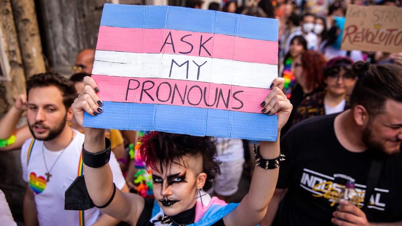 A participant holds a placard with the colors of the trans