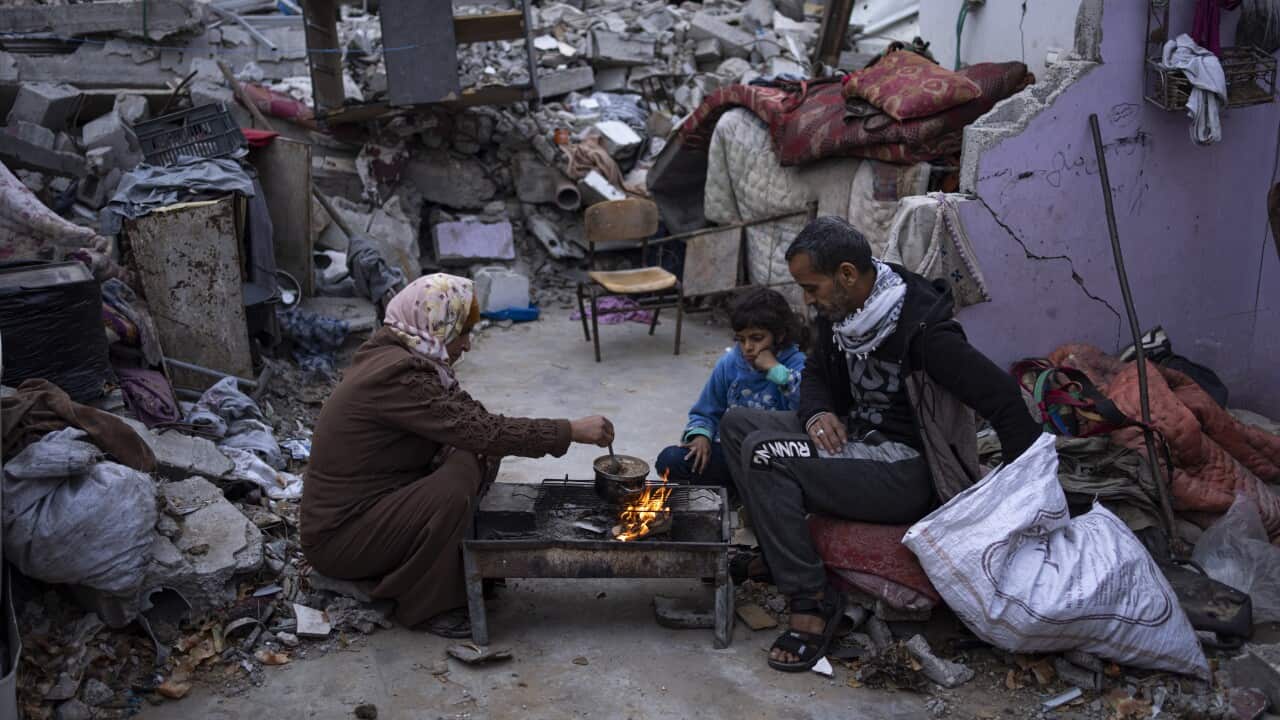 A family prepares food outside their destroyed home.