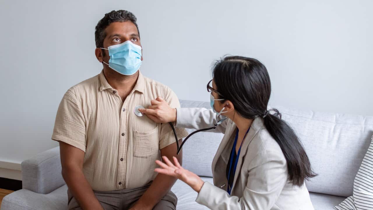 Doctor and patient wearing protective face masks during at home medical appointment
