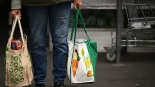 A person holding shopping bags with Woolworths signange
