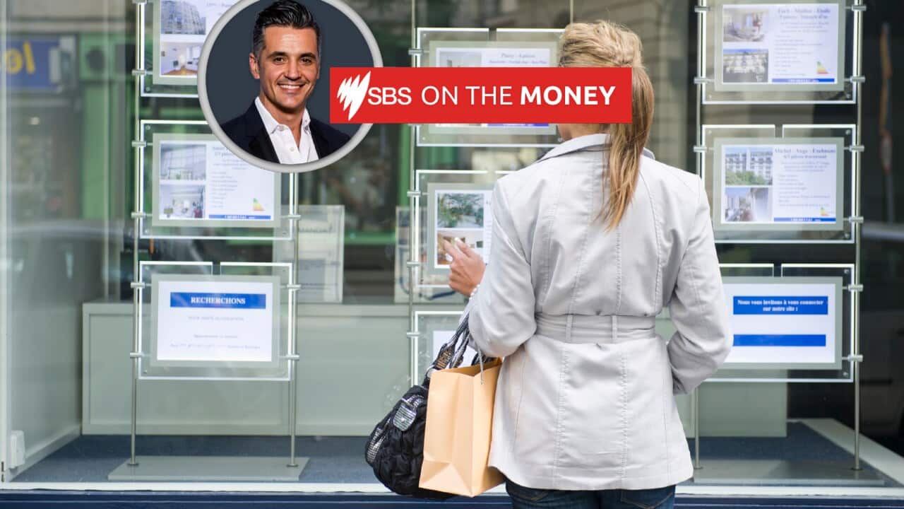 A woman looks at ads for properties outside a real estate agent.