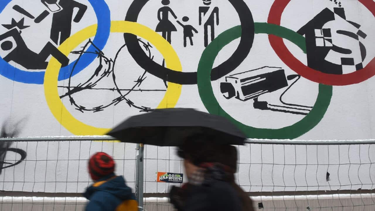 Passer bys walking past a poster with the Olympic rings in Hamburg