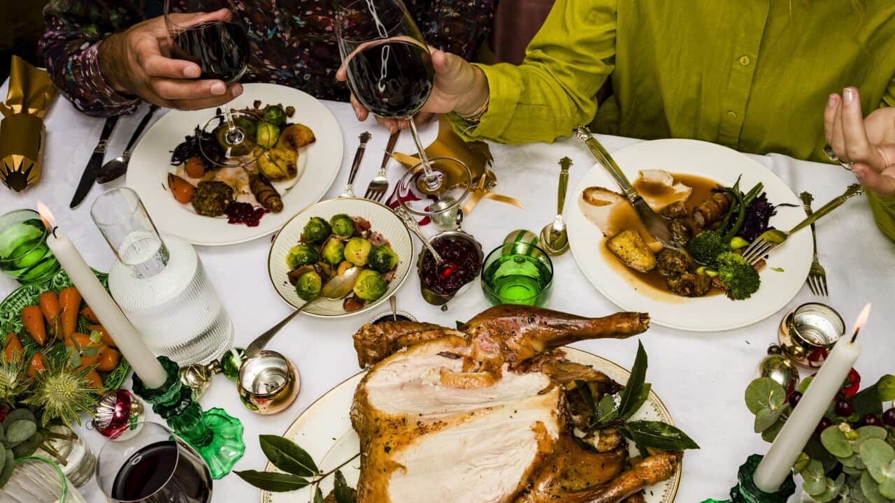 Close-up aerial view of people sitting at at table having a Christmas dinner, including roast chicken.
