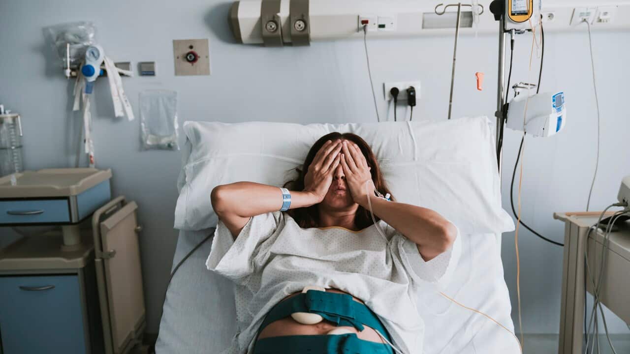 Stressed pregnant woman lying on bed in hospital