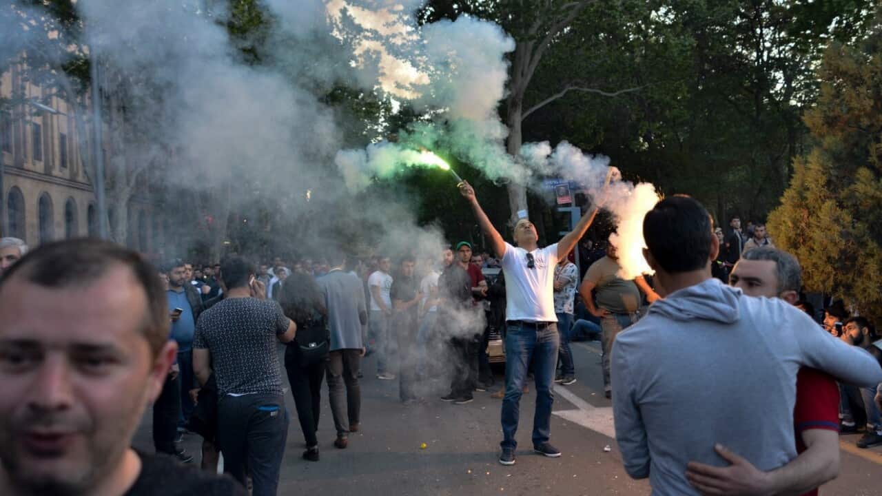 A man waves flares while protesters gathering in the center of Yerevan, Armenia, Wednesday, April 25, 2018.