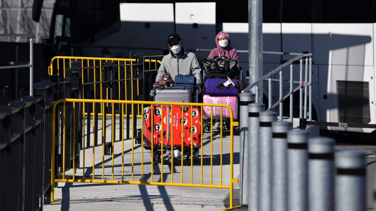Un viajero de regreso se prepara para subir a un autobús de cuarentena en el aeropuerto internacional de Sidney Sydney,(AAP Image/Joel Carrett)