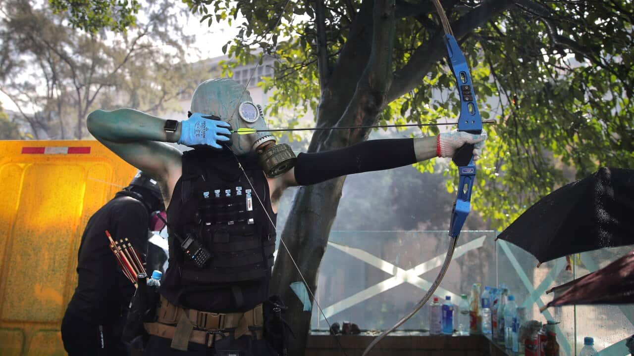 A protestor prepares to fire a bow and arrow during a confrontation with police at the Hong Kong Polytechnic University