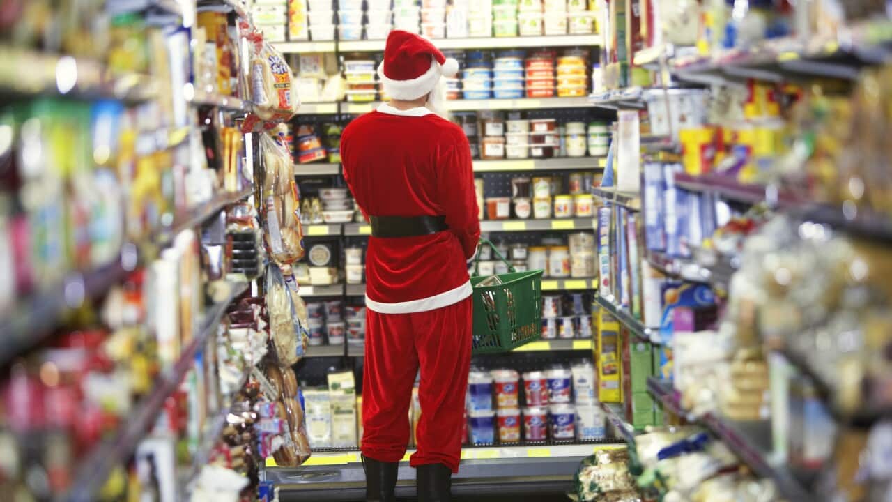 Man dressed as Santa Claus standing in supermarket, rear view