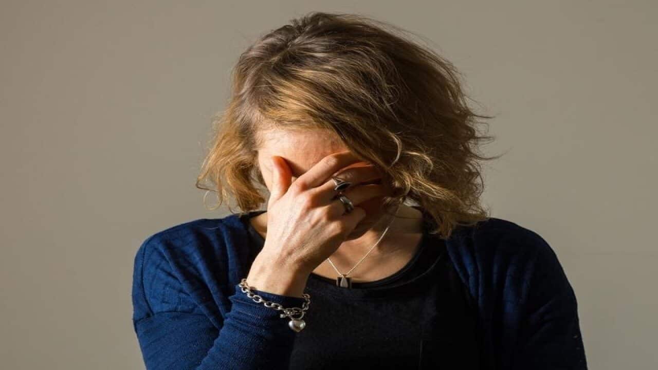 A woman with her head in her hands suffering a migraine.