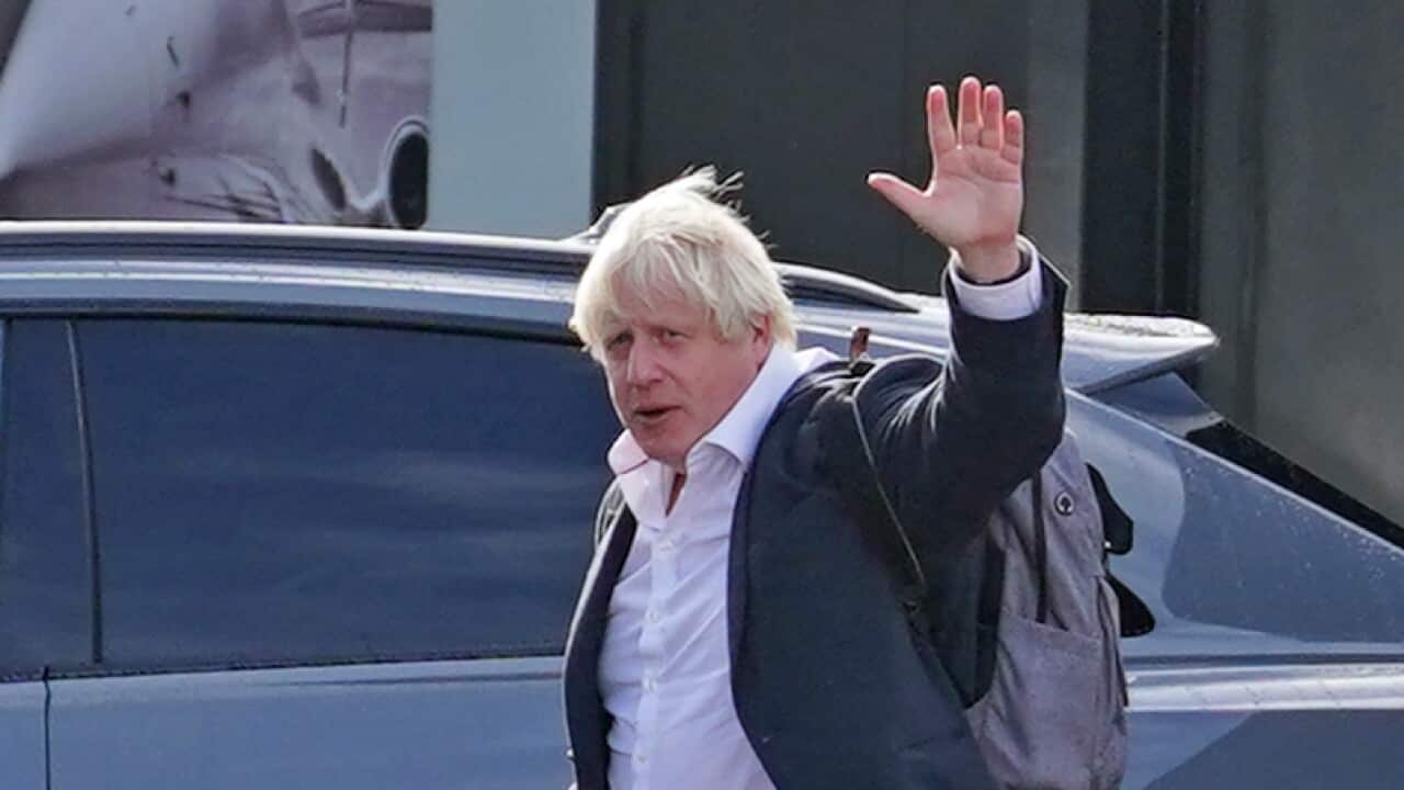 A man walking to a car while waving.