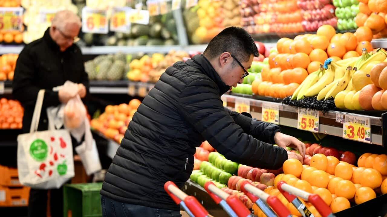 A worker arranges apples at a market in Melbourne (AAP)