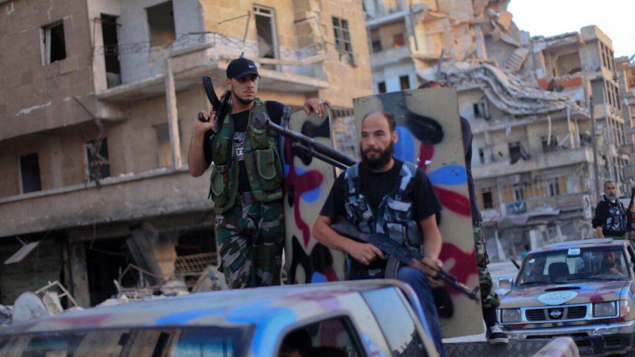 Armed rebels from the Islamic Front, an umbrella of Islamist rebel groups in Syria, drive past buildings damaged during fighting between Syrian government forces and opposition forces on July 19, 2014 in Aleppo. (AFP)
