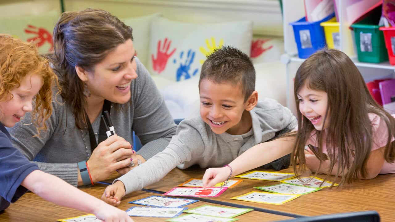 A teacher helping students with project in a classroom.