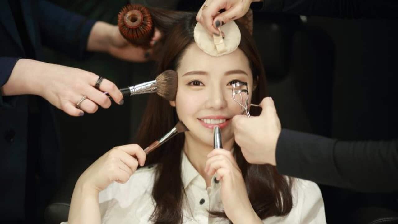 Woman having makeup applied by stylists