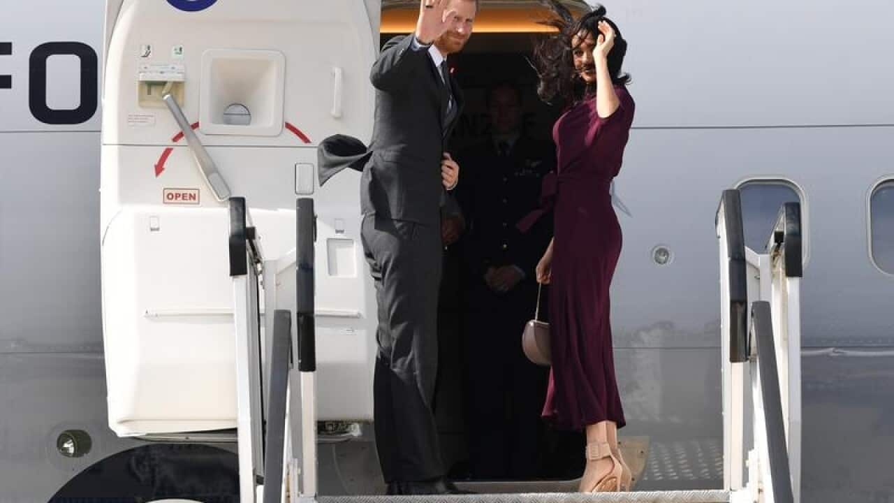 Prince Harry and Meghan wave as they board a plane at Sydney Airport.