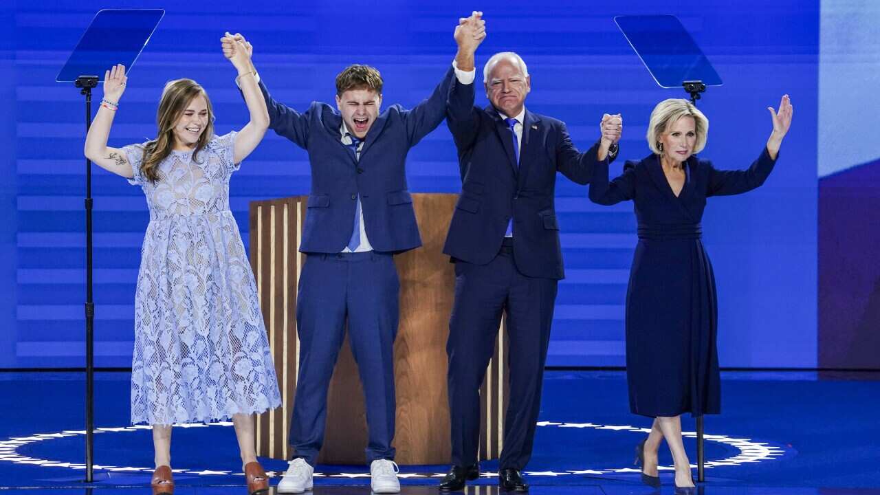 An older man, older woman, younger woman and younger man hold hands and put them up in celebration