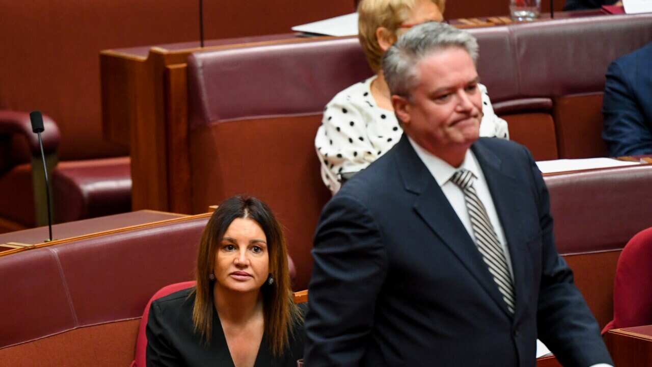 Crossbench Senator Jacqui Lambie reacts as the leader of the government in the Senate Mathias Cormann walks past during debate in the Senate chamber at Parliament House in Canberra, Wednesday, December 4, 2019. (AAP Image/Lukas Coch) NO ARCHIVING