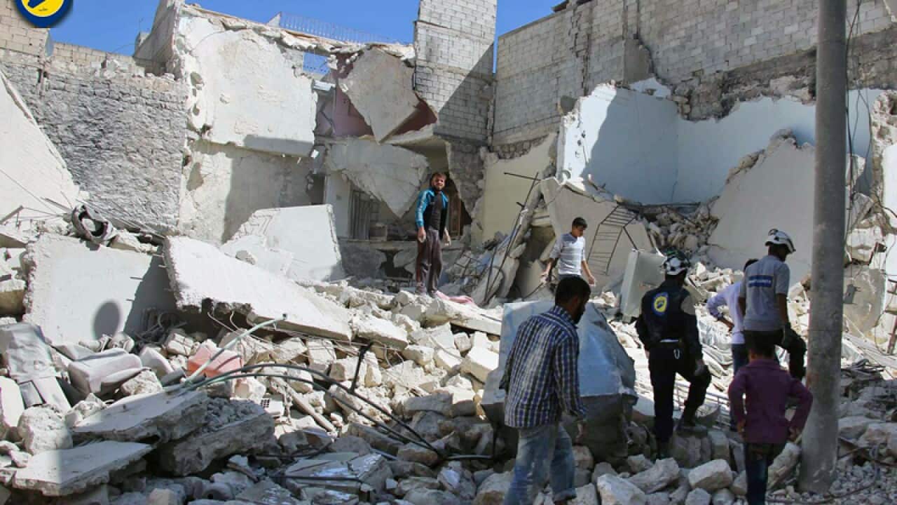 People inspect damaged buildings after airstrikes in Aleppo