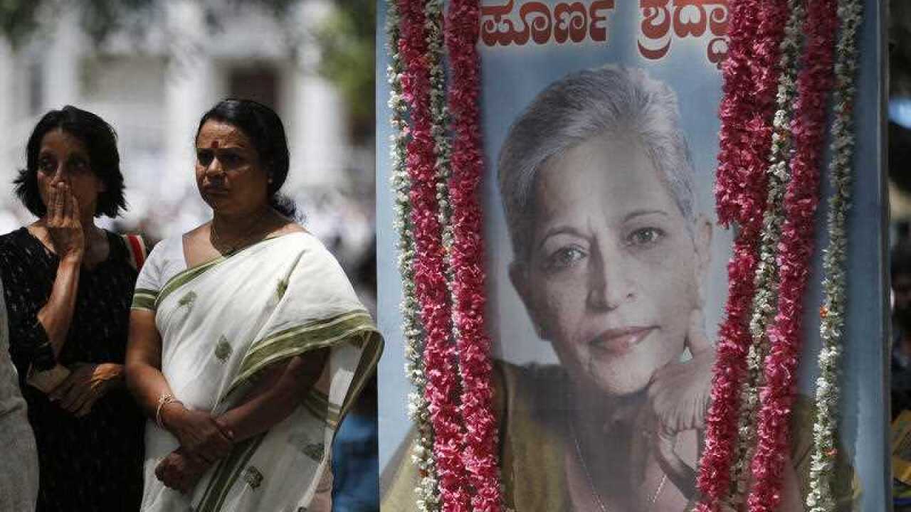 Mourners stand next to a portrait of Indian journalist Gauri Lankesh.