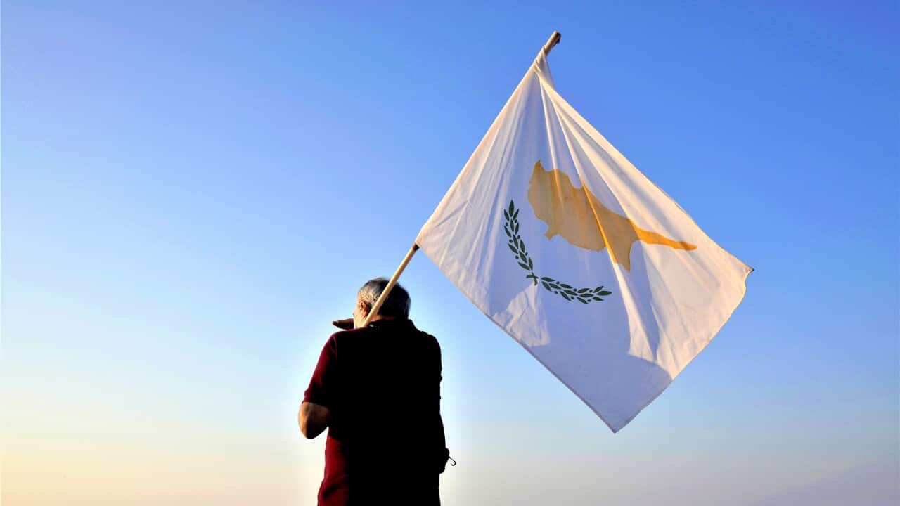 A man with a Cyprus flag stands in front of the Varosha or Famagusta, abandoned city.