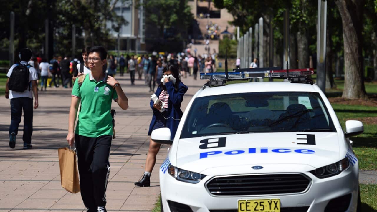 Students pass by a police car at the University of NSW in Sydney