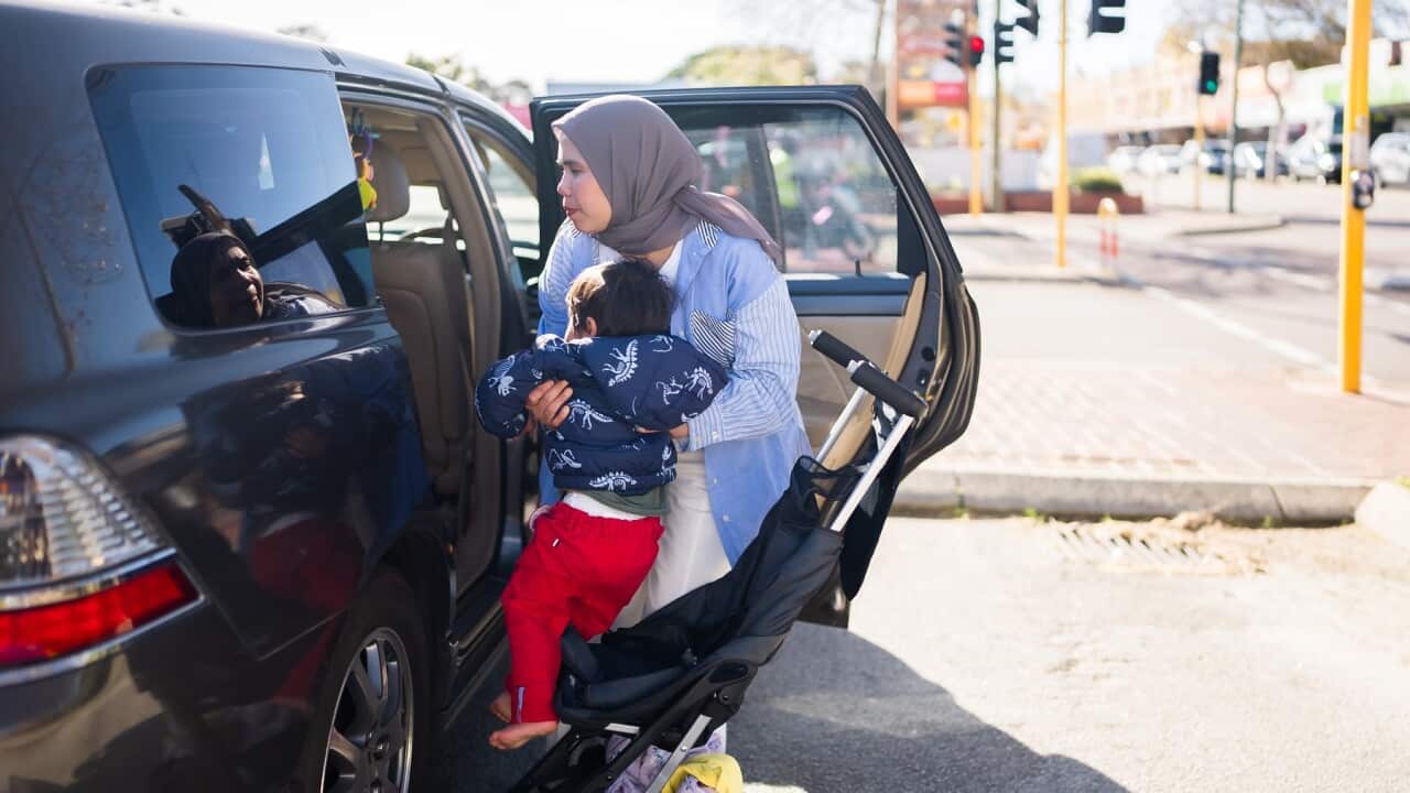 Mother carefully gets her baby boy in on the car