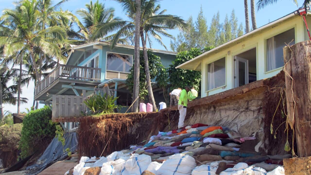 sandbags are piled up in front of properties damaged by severe beach