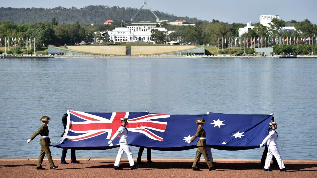 Defence personnel march past with the Australian flag at an Australia Day Citizenship Ceremony and Flag Raising event in Canberra, Saturday, January 26, 2019. (AAP Image/Mick Tsikas) NO ARCHIVING