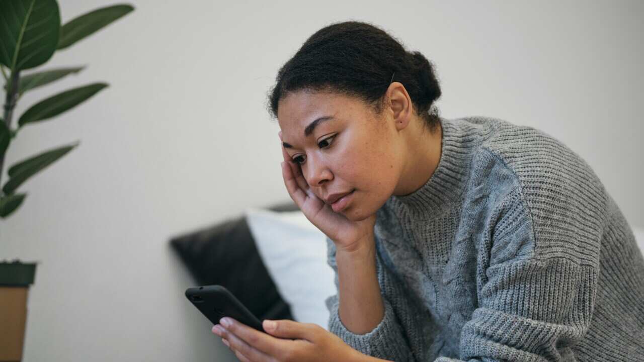 A woman looking stressed reading her phone