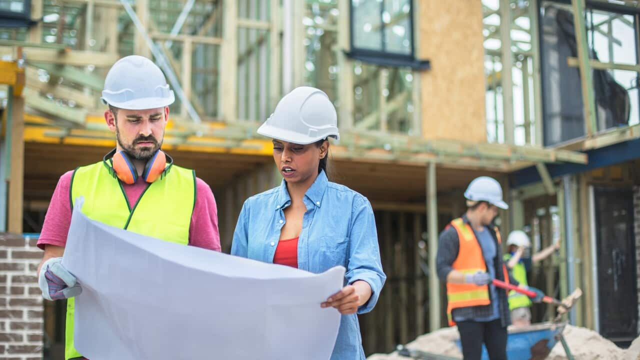 Architect showing plans to foreman on building site