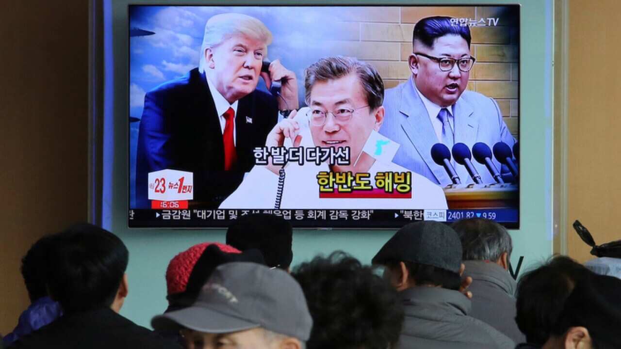 A TV screen showing images of North Korean leader Kim Jong-un, South Korean President Moon Jae-in and US President Donald Trump at Seoul Railway Station