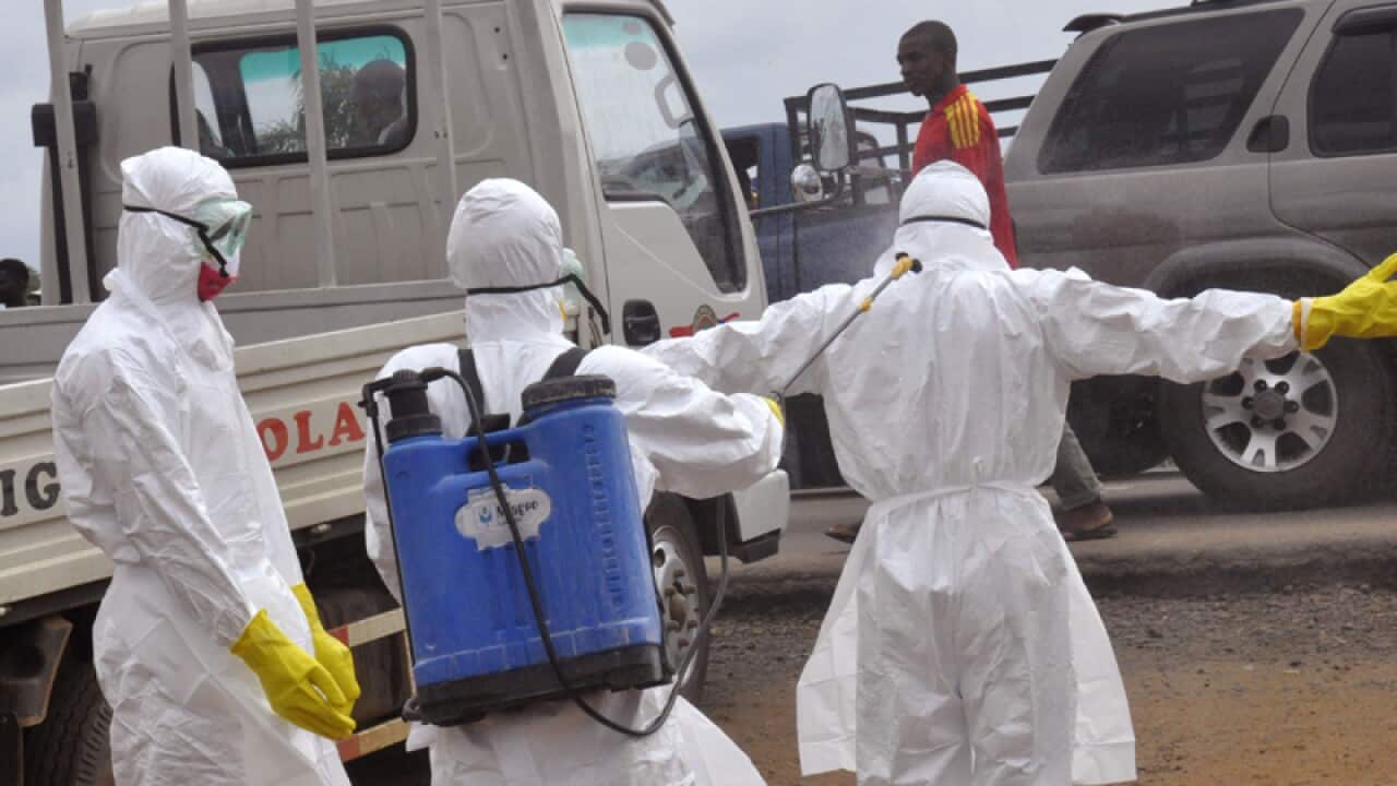 Liberian health care workers spray each other with disinfectant.