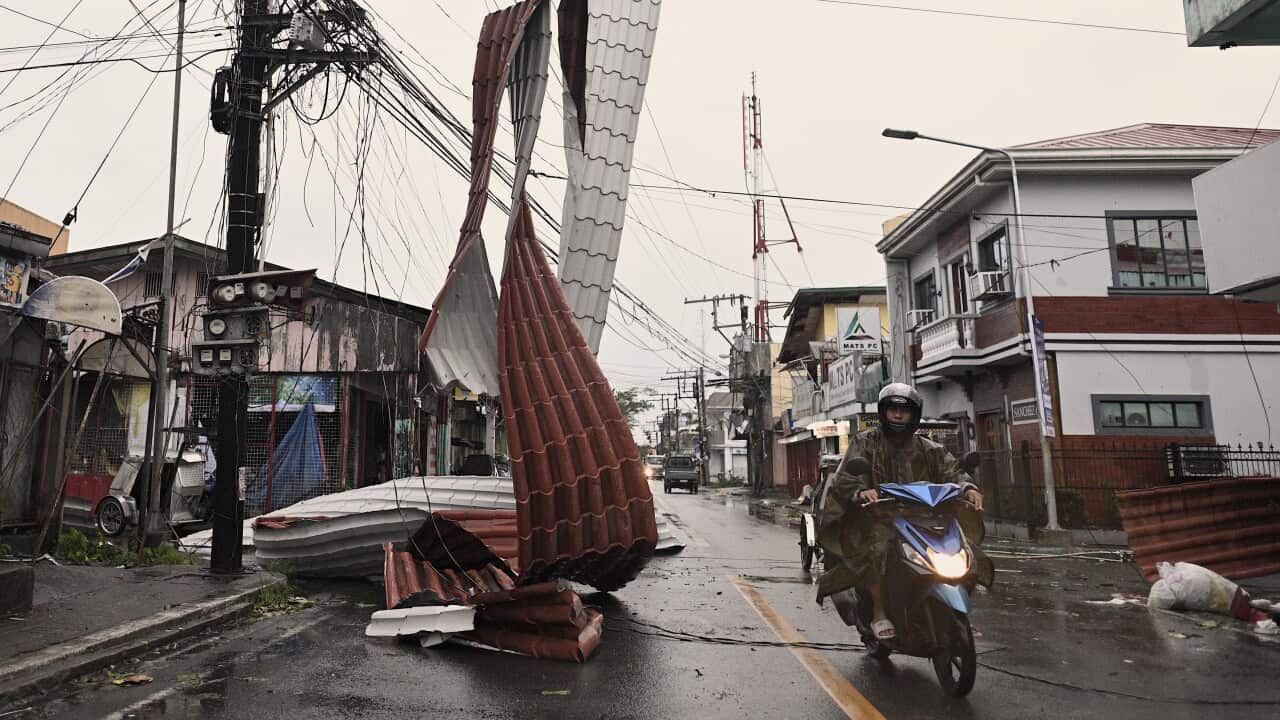 Philippines Asia Motorists ride past a part of a roof suspended on electric wires