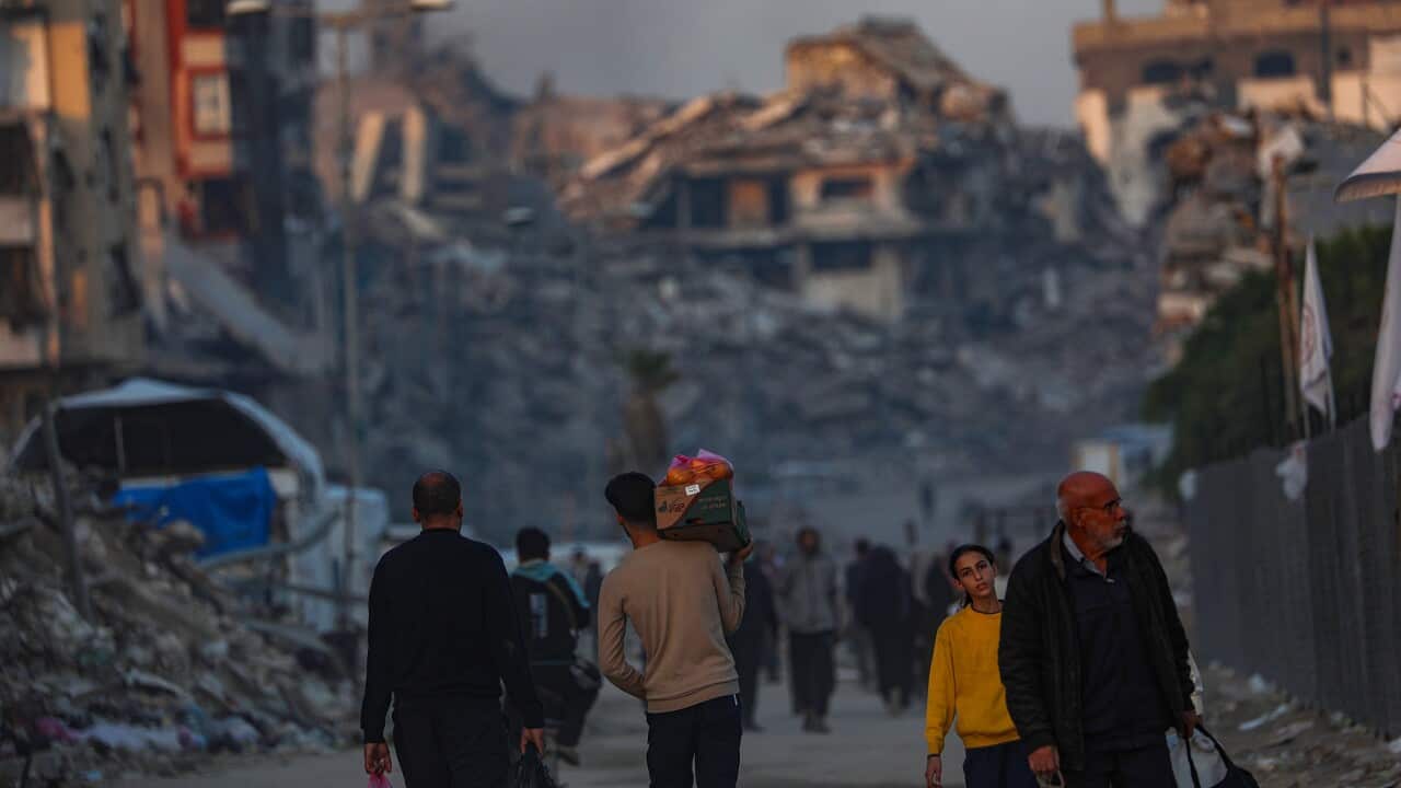 Palestinians walk between destroyed buildings in northern Gaza City