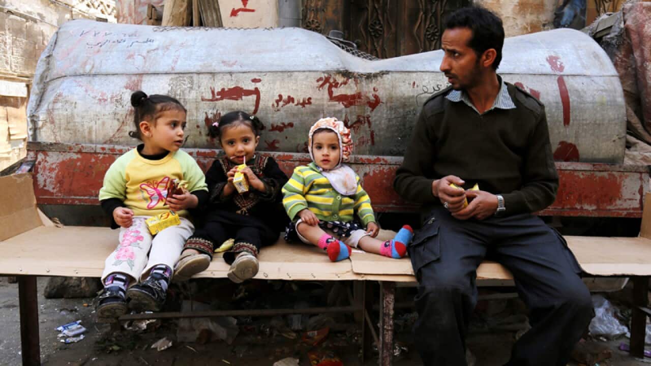 A Yemeni sits near three children in the old city of Sana'a, Yemen