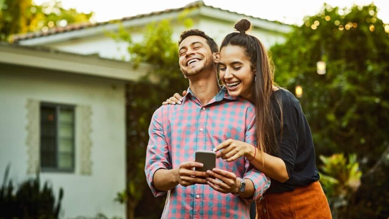 Happy couple looking at smart phone in back yard