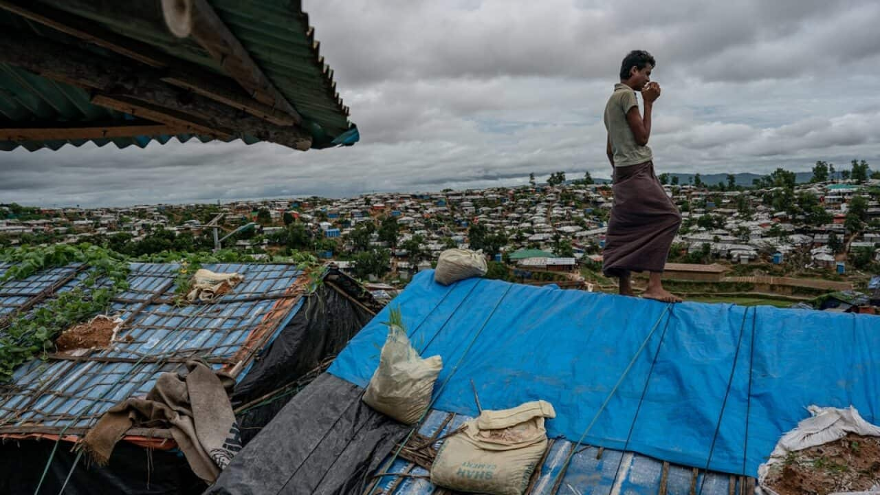 A Rohingya refugee stands atop his makeshift shelter in Cox’s Bazar, Bangladesh.