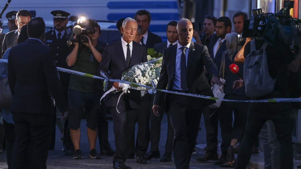 A man carries flowers, paying respect to victims of a funicular crash in London.