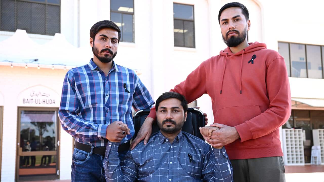 Two men standing and one man seated