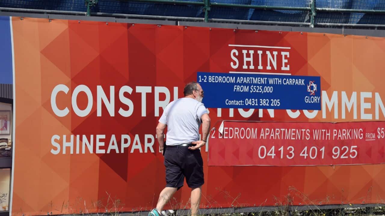 A man walks past a new apartment complex under construction
