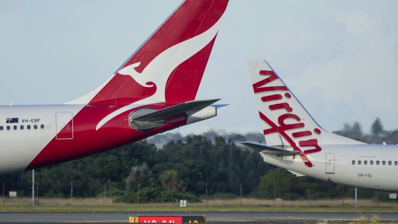 A Qantas and Virgin passenger jets pass as they taxi at Sydney Airport