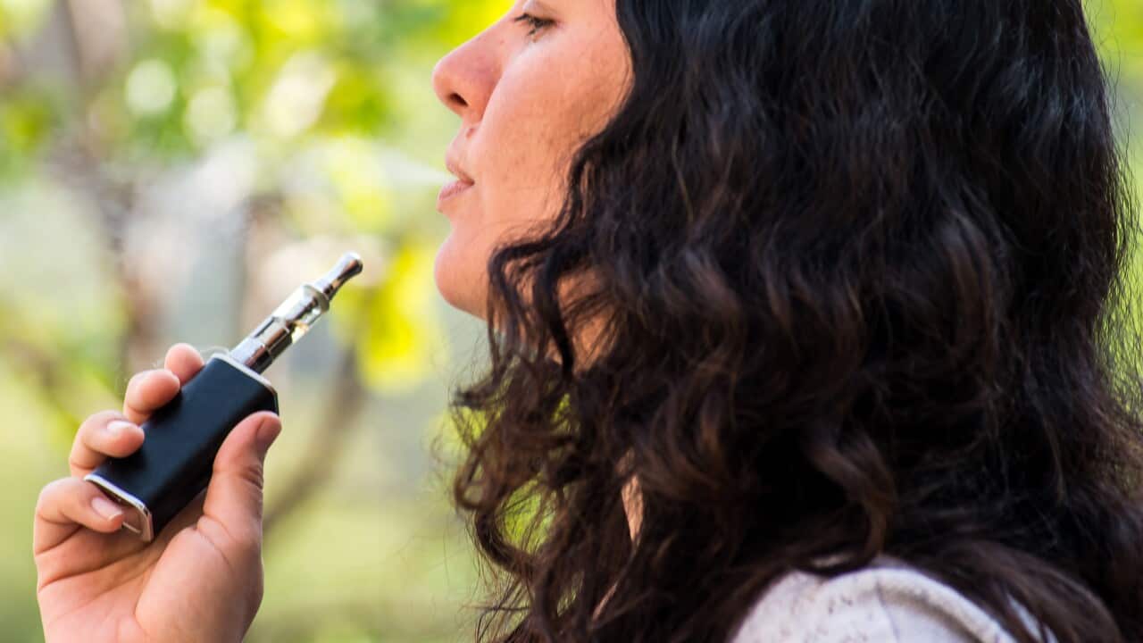 Mature woman outdoors, smoking electronic cigarette