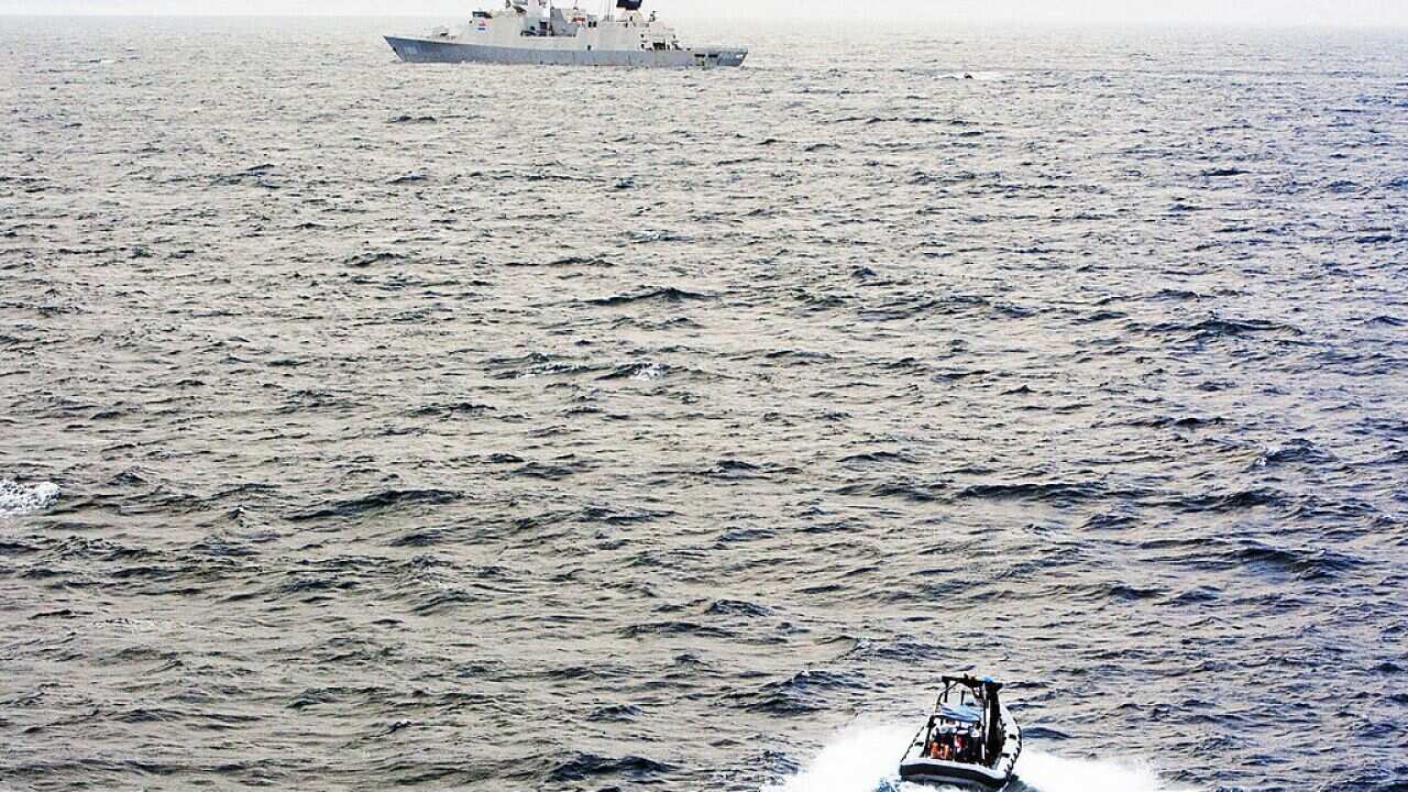 A small boat speeds towards a ship in the distance