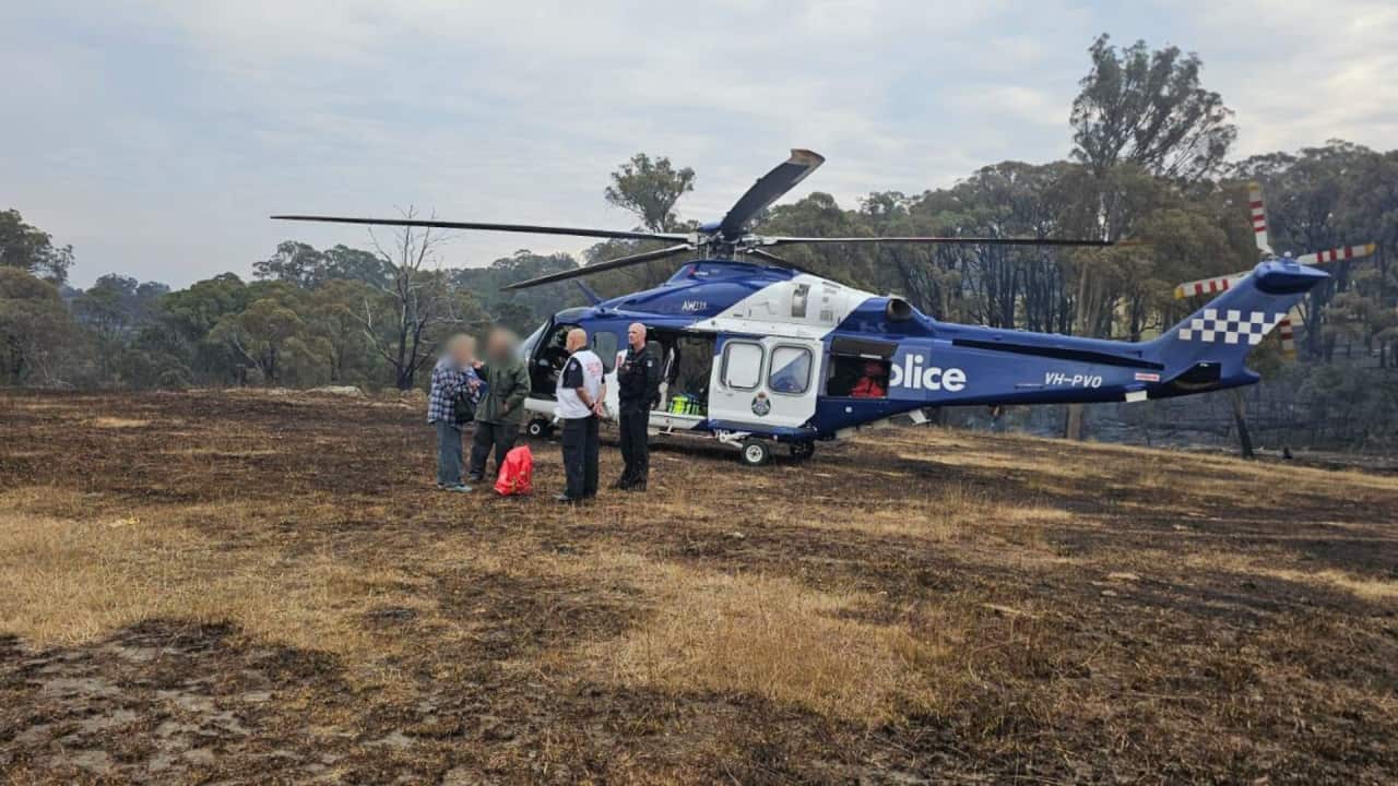 Four people stand near a helicopter