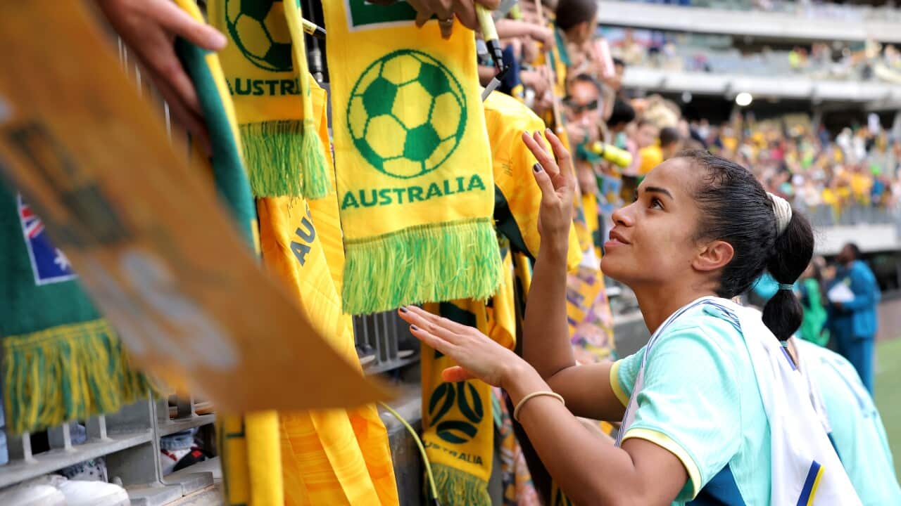 A woman signs football fans' autographs