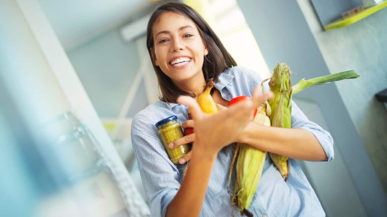 Woman picking up some fruits and veggies from the fridge
