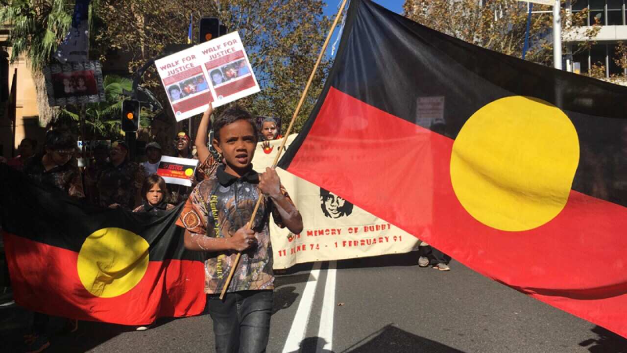 A child holds an Aboriginal flag during a protest in Sydney