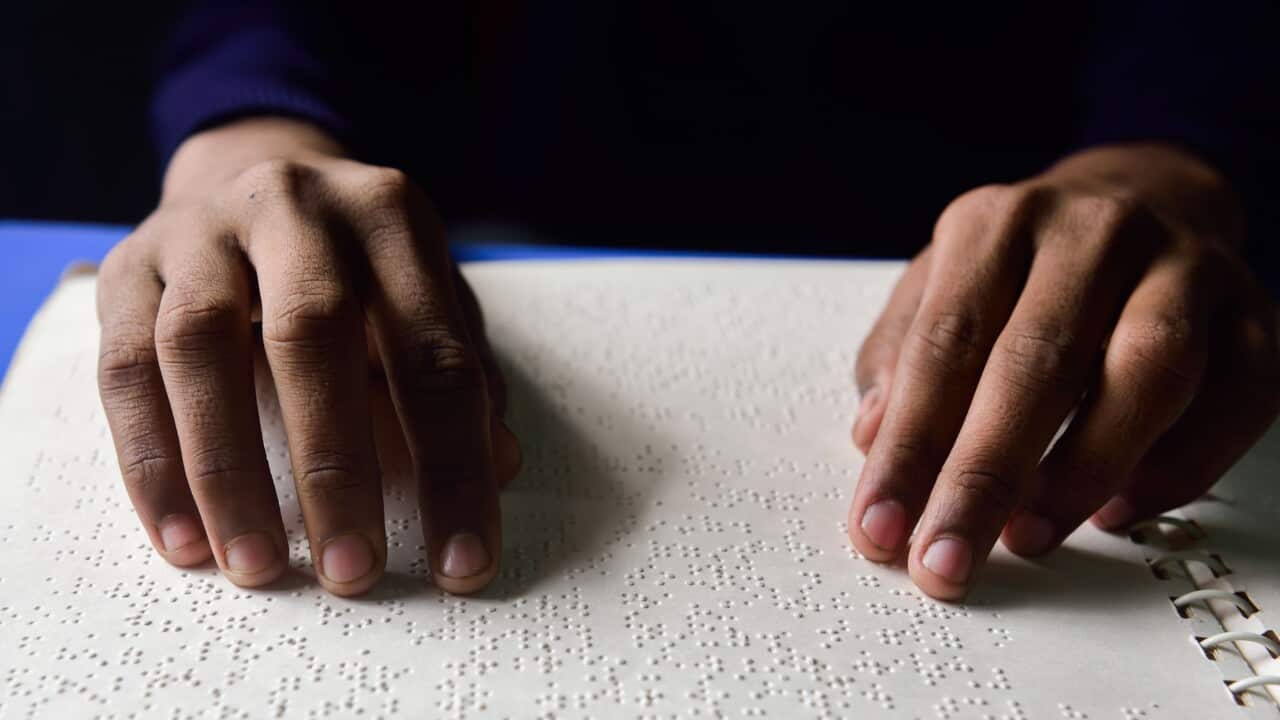 Two hands reading Braille on paper